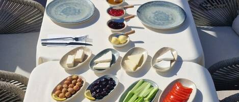 Una mesa servida con diversos alimentos para el desayuno, como huevos, pan, frutas y verduras.