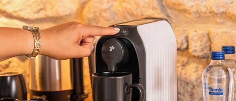 A coffee maker on a wooden counter with a stone wall in the background.