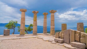 De vieilles colonnes de pierre, avec vue sur un lac et des montagnes en arrière-plan.