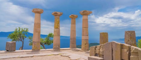 Ancient stone columns with a view of a lake and mountains in the background.