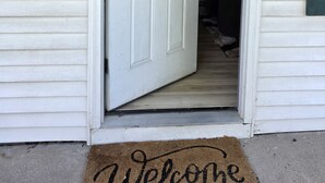 A white door with a 'Welcome' mat at the entrance, a mailbox, and a house number '3018'. - Charming 3-bedroom bungalow in pleasant Indianapolis with WiFi, AC, (Indianapolis)