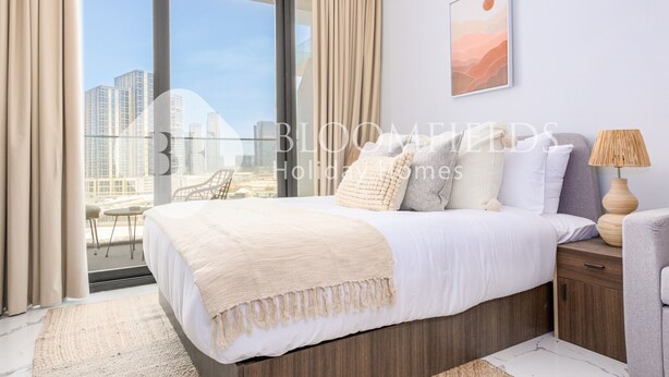 Une chambre d’hôtel moderne avec un grand lit, une vue sur la ville et un tableau représentant un paysage urbain accroché au mur.