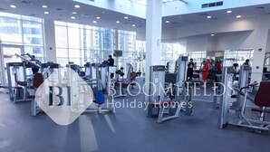Une salle de sport spacieuse, équipée de divers appareils d’exercice et dotée de grandes fenêtres laissant entrer la lumière naturelle.
