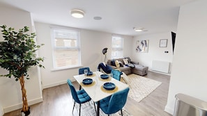 Unwind in the bright living space, featuring a comfortable sofa bed and large Smart TV—perfect for relaxed evenings, movie nights, or accommodating an extra guest with ease