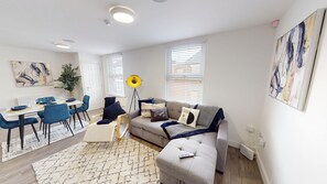 Unwind in the bright living space, featuring a comfortable sofa bed and large Smart TV—perfect for relaxed evenings, movie nights, or accommodating an extra guest with ease