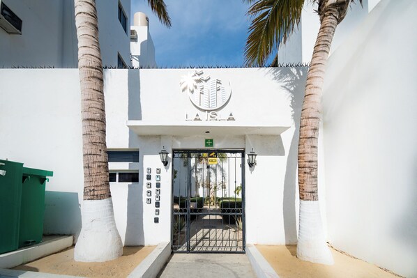 A gated entrance with a sign reading "LA ISLA" and palm trees flanking the gate.