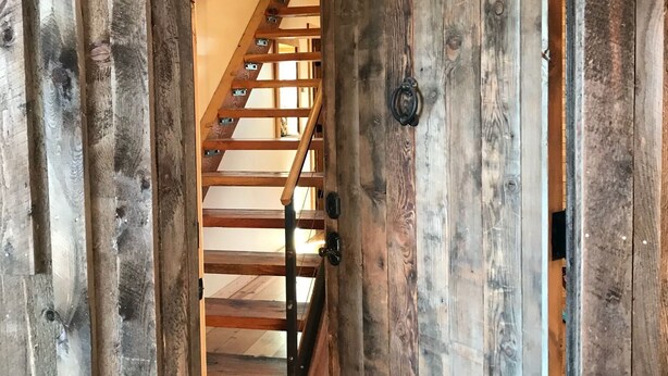 A wooden door with a metal latch and a metal handle, leading to a wooden staircase with metal railings. - Oso Verde Ranch, a natural oasis, is located just a mile from downtown Mancos (Mancos)