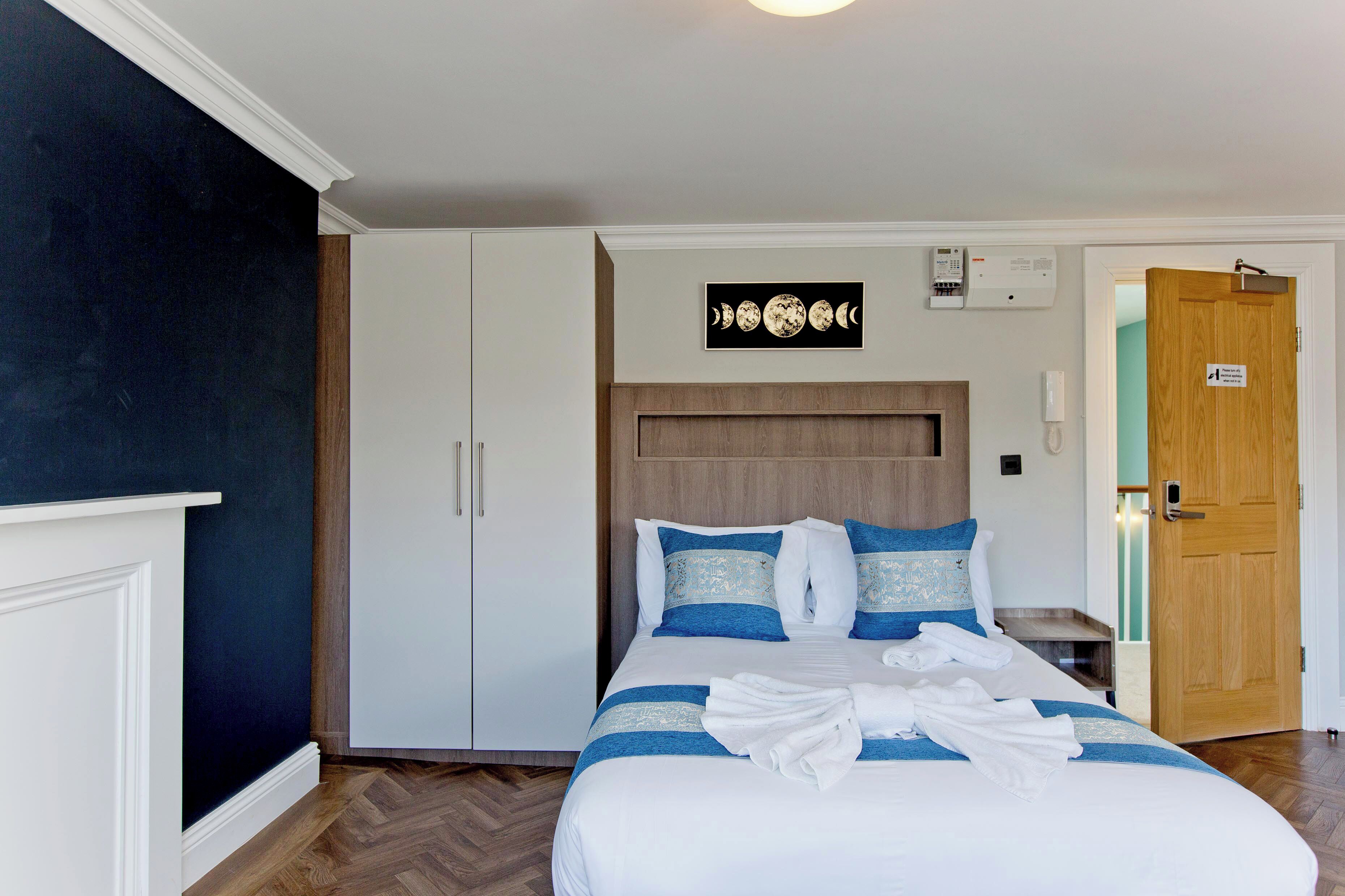 Een hotelkamer met een bed, een witte kast en een houten deur.