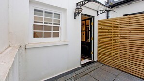 Un edificio blanco con ventana, puerta y cerca de madera.