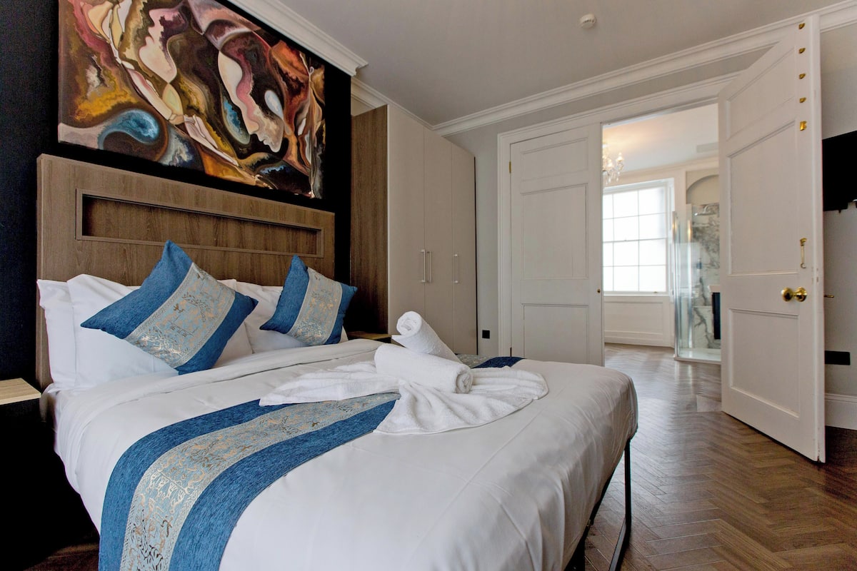 A hotel room with a large bed, a wooden headboard, and a painting on the wall.
