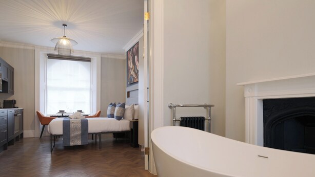 Un baño moderno con una bañera independiente, chimenea y un comedor con mesa y sillas.