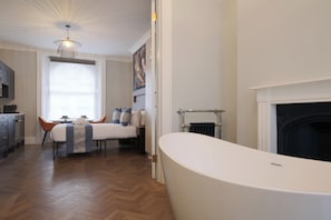 A modern bathroom with a freestanding bathtub, a fireplace, and a dining area with a table and chairs. - Imperial York Street Apartments (London)