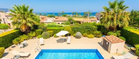 A swimming pool with lounge chairs and a view of the sea.