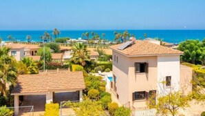 A coastal residential area with houses, palm trees, and a clear view of the sea. - Villa Fortuna (Polis)
