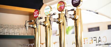 A row of beer taps with labels such as "Alhambra," "Sangria," and "Maestra Dunkel."