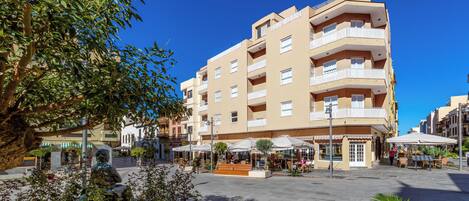 A multi-story building with balconies, outdoor seating, and a central courtyard.