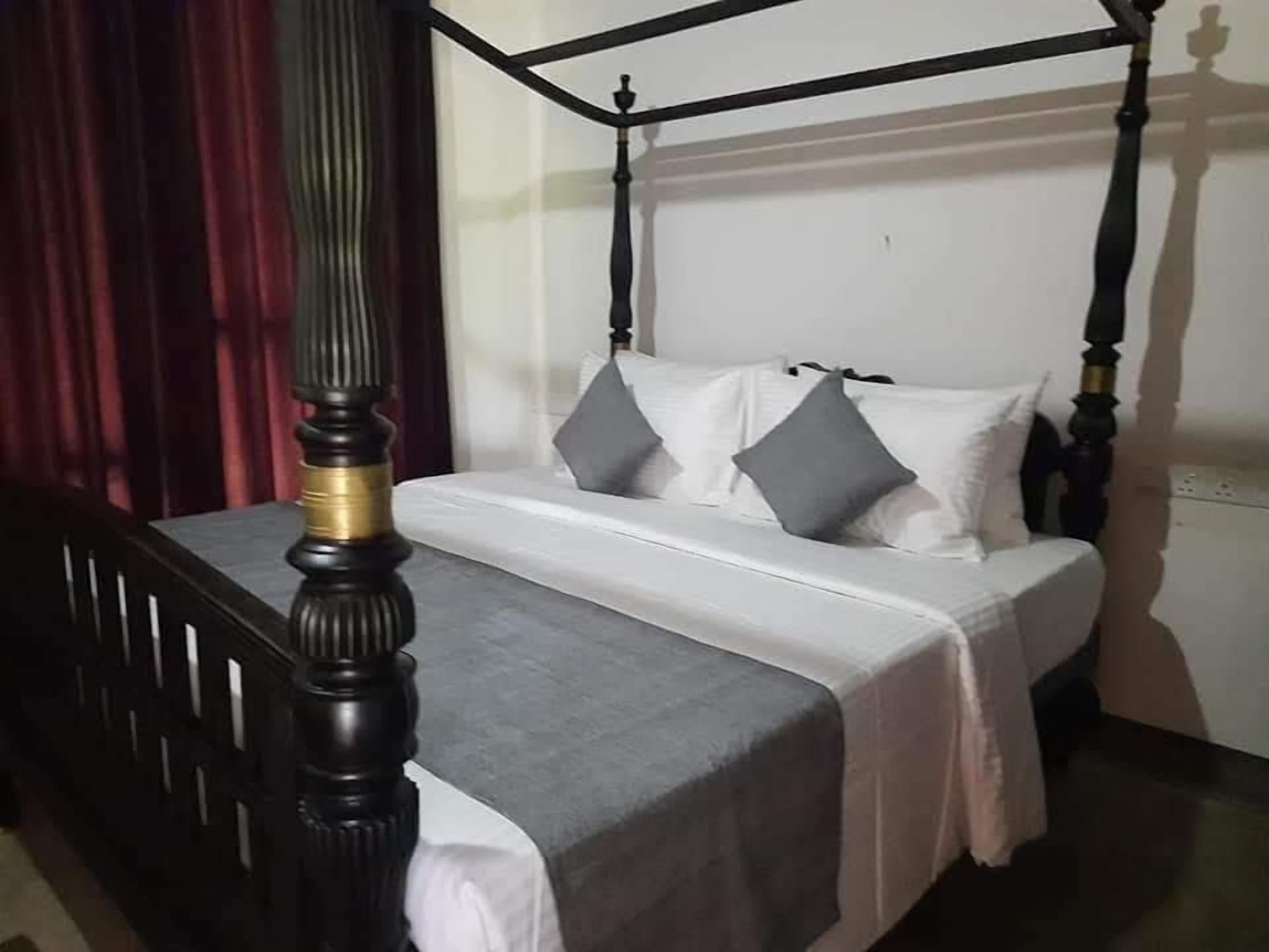 Ein Himmelbett mit weißer Bettdecke und grauen Kissen.