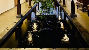 A corridor with a water feature, wooden columns, and traditional architecture. - The Nature Palace Villa (Uragasmanhandiya)