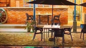 An outdoor seating area with a brick wall, a large umbrella, and a table with chairs. - The Nature Palace Villa (Uragasmanhandiya)
