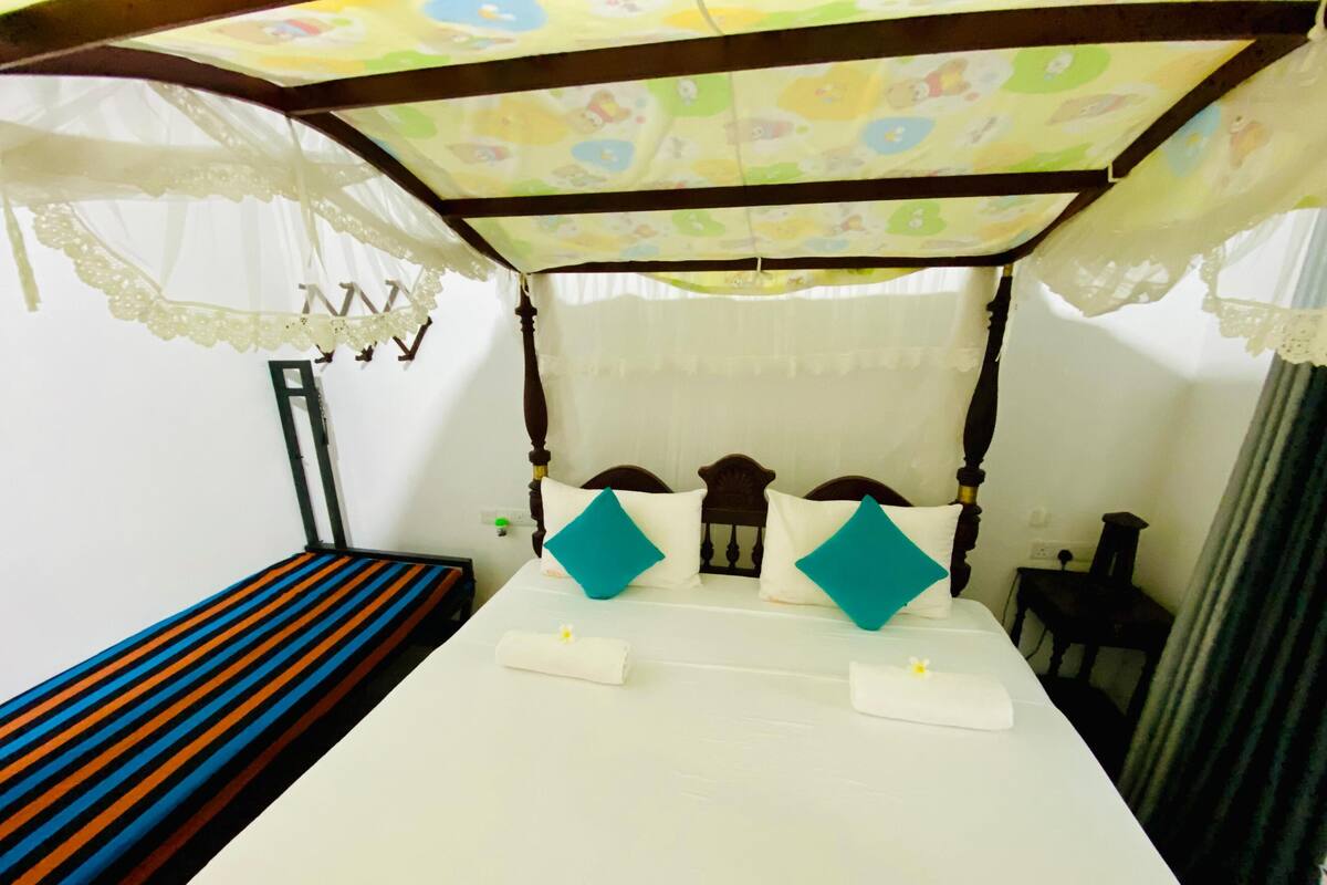 A bed with a canopy, a bedside table, and a striped bench.