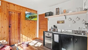 Una cocina moderna con armarios de madera, microondas integrado y pileta de acero inoxidable.