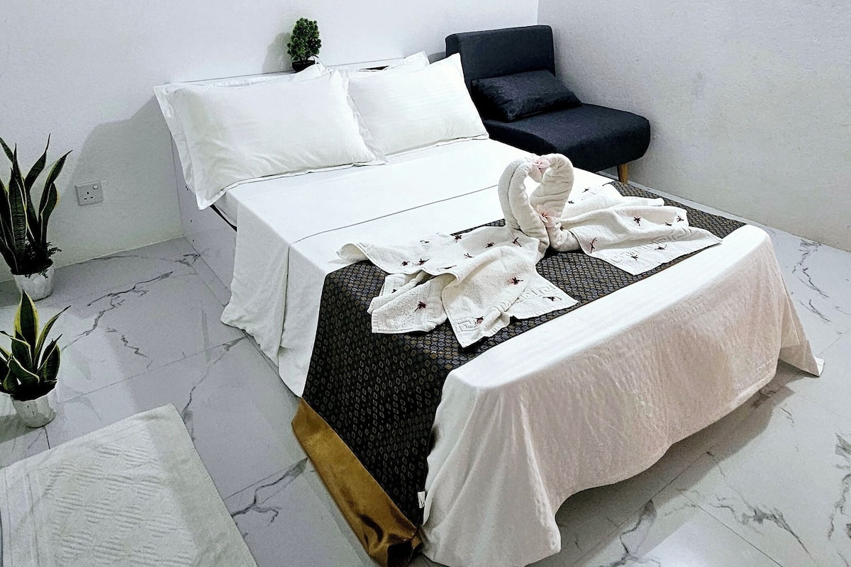Ein Schlafzimmer mit einem Bett, einem kleinen Sofa und einer Zimmerpflanze.