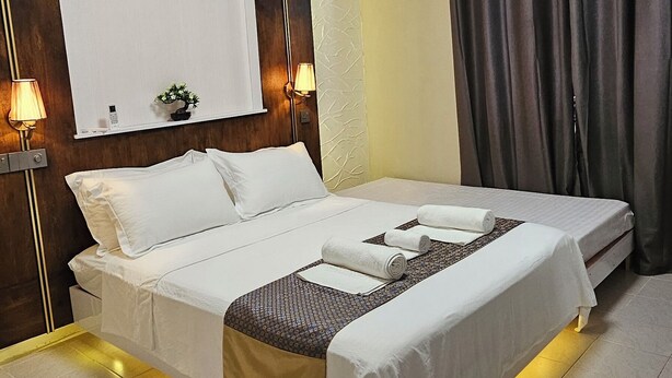 Une chambre d’hôtel équipée d’un lit, de lampes de chevet, d’un ventilateur de plafond, d’un appareil de climatisation et d’une fenêtre avec des rideaux.