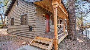 A log cabin with a wooden porch, a red door, and a small window. - Timber Lodge Cabin #21 (Colorado Springs)