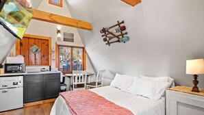 Een gezellige kamer met een bed, bureau en kitchenette.