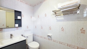 Een badkamer met toilet, wastafel, spiegel en handdoekhouder.