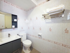 Een badkamer met toilet, wastafel, spiegel en handdoekhouder.