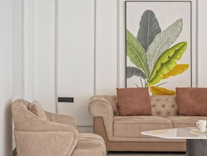 Een zithoek met een beige bank, twee bruine kussens en een witte salontafel.