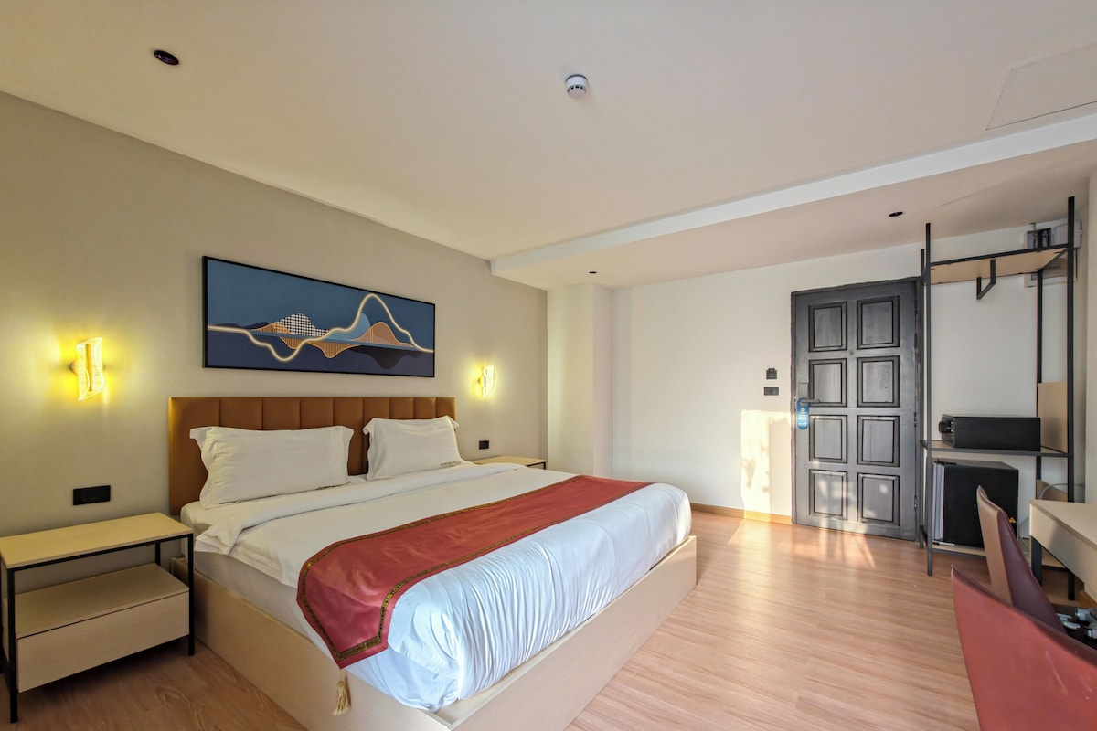 Een hotelkamer met een bed, nachtkastjes, een bureau en een stoel.