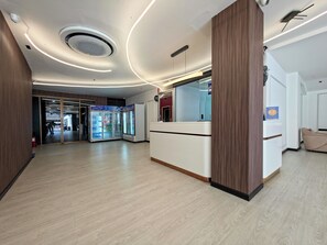 Ein moderner Empfangsbereich mit einem Holzbüro, einer Glastrennwand und einem Automaten.