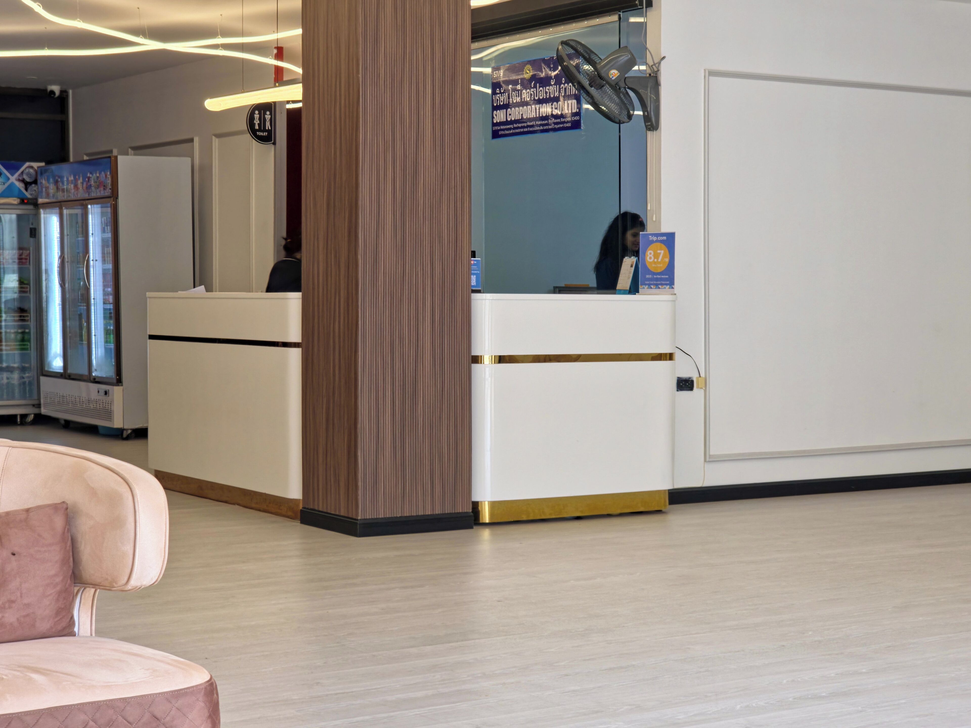 Zona de recepción con mostrador, refrigerador y ventilador de pared.