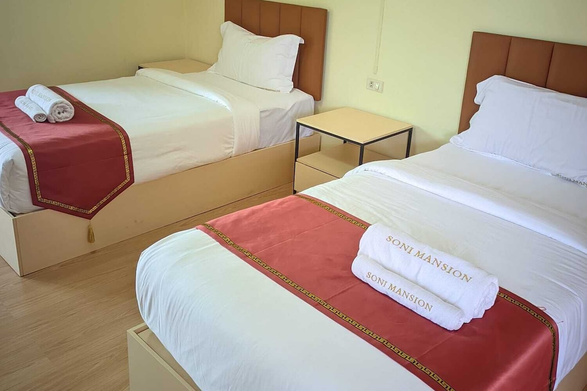 Een hotelkamer met twee bedden, een kleine tafel en een wandairconditioner.