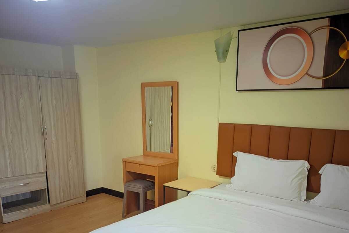 Een hotelkamer met een bed, een bureau, een kledingkast en een spiegel.