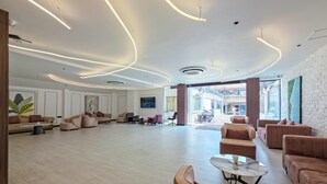 Eine geräumige Lobby mit modernen Möbeln, einem großzügigen Sitzbereich und Blick auf die Straße durch Glastüren.