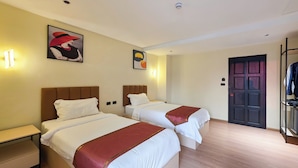 Een hotelkamer met twee bedden, een garderobe en een deur.