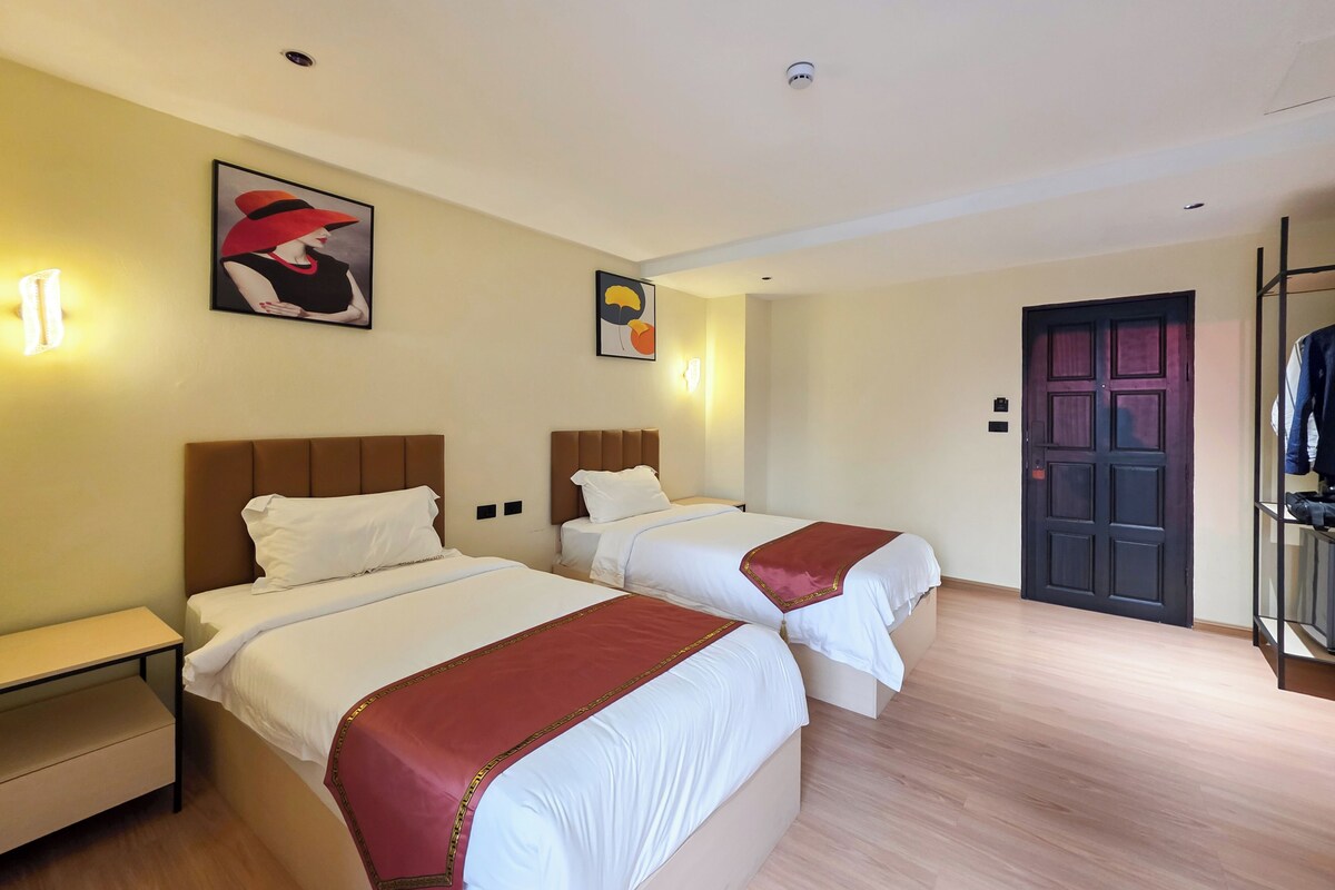 Een hotelkamer met twee bedden, een garderobe en een deur.