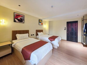 Een hotelkamer met twee bedden, een garderobe en een deur.