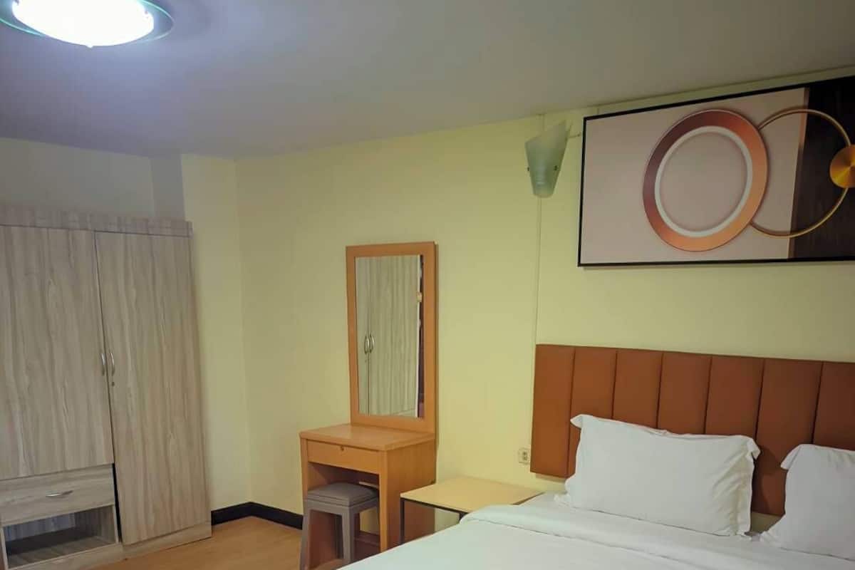 Una habitación de hotel con cama, escritorio, armario y espejo.
