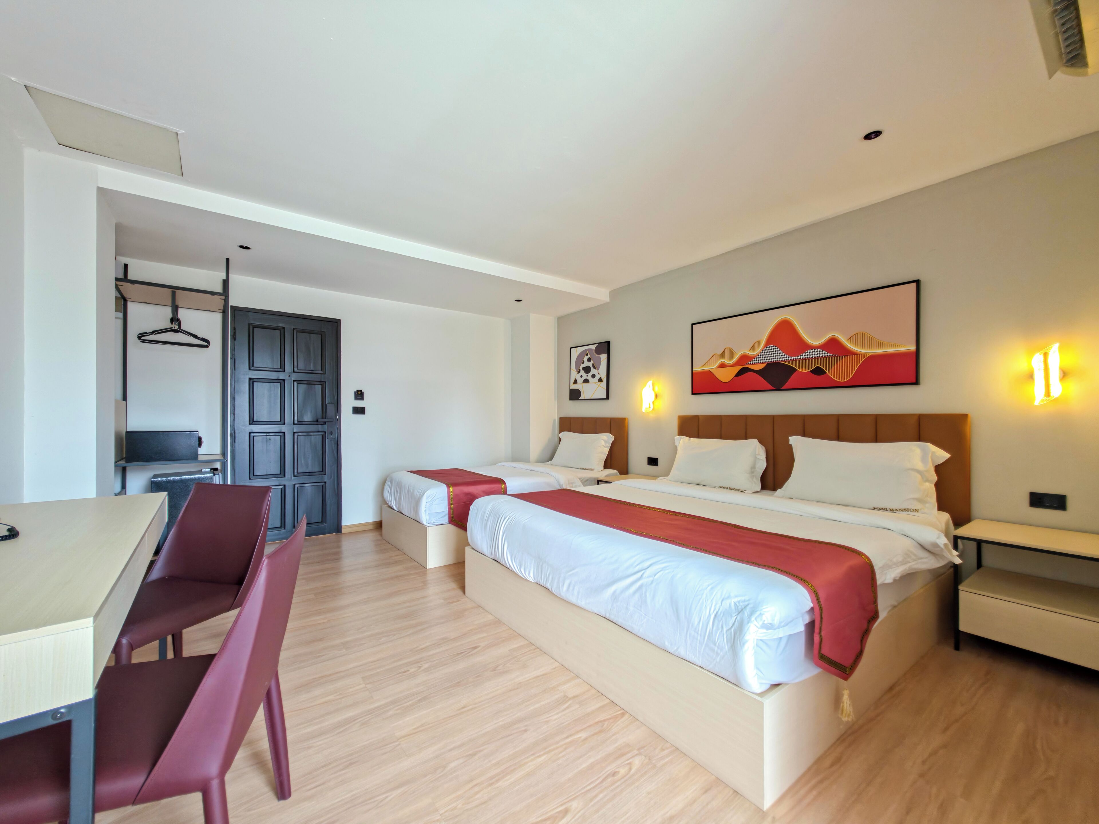 A hotel room with two beds, a desk, and a chair.