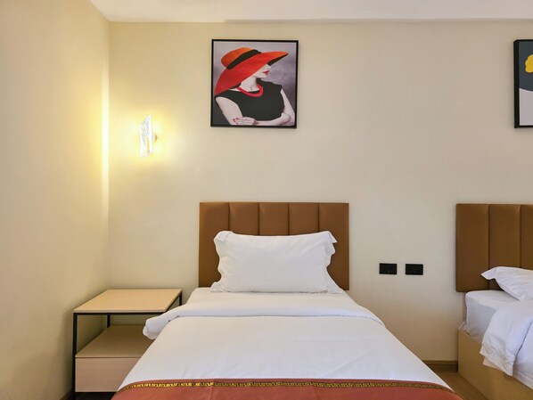 A hotel room with a bed, bedside tables, a wall-mounted light, and a framed picture. - Hotel Soni Mansion Pratunam (Bangkok)