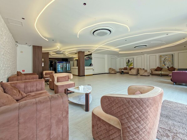 Een ruime lobby met moderne zitplaatsen, een receptiebalie en een groot kunstwerk aan de wand.