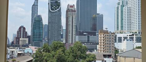 Un paisaje urbano con edificios modernos de gran altura, una combinación de estructuras residenciales y comerciales, y un primer plano arbolado.