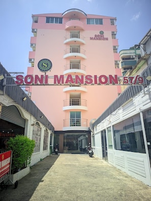 Een roze gebouw met het bord 'SONI MANSION STA' dat een hotel aangeeft.