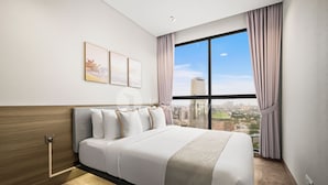 A modern hotel room with a large bed, a city view, and a wooden headboard. - Havari by Kozystay - Sudirman (Jakarta)