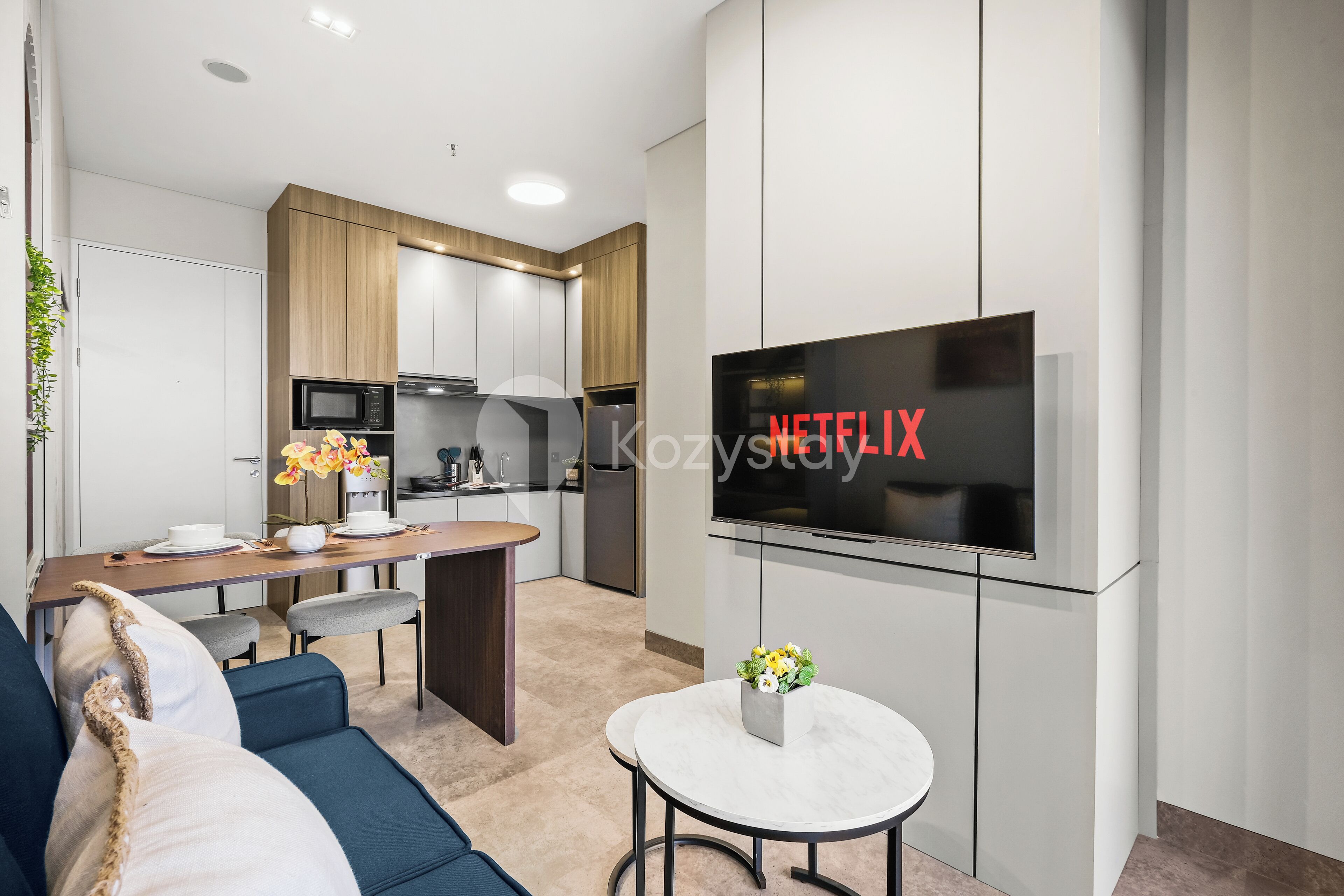 A modern kitchen with white cabinets, a wooden countertop, and a built-in microwave.