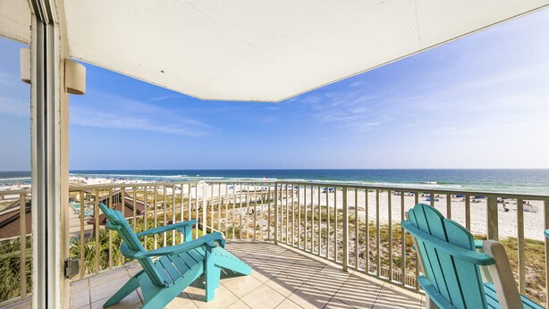 A balcony with two turquoise Adirondack chairs, a tiled floor, and a view of the beach and ocean. - Four Winds 301 (Orange Beach)